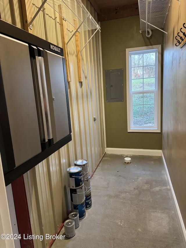 corridor featuring a high ceiling, concrete floors, and electric panel