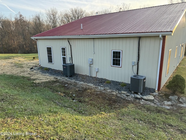 view of side of home featuring a lawn and central AC