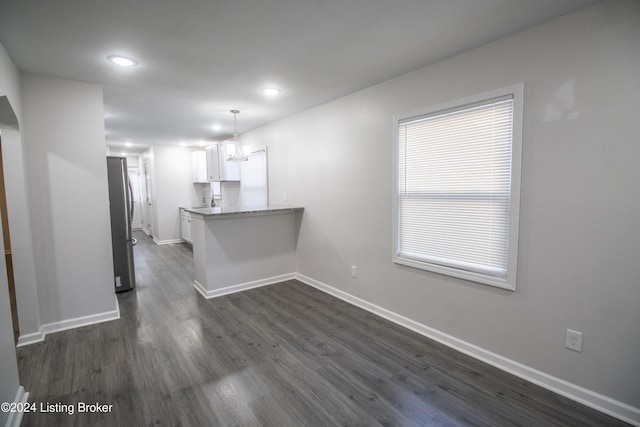 kitchen with white cabinets, stainless steel fridge, dark hardwood / wood-style flooring, and kitchen peninsula