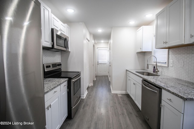 kitchen with white cabinetry, sink, light stone countertops, dark hardwood / wood-style flooring, and appliances with stainless steel finishes