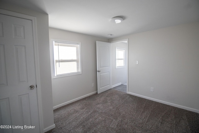 empty room featuring dark carpet and a healthy amount of sunlight