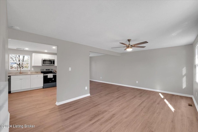 unfurnished living room featuring ceiling fan, light hardwood / wood-style flooring, and sink