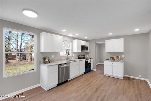 kitchen featuring white cabinets, appliances with stainless steel finishes, and light hardwood / wood-style flooring