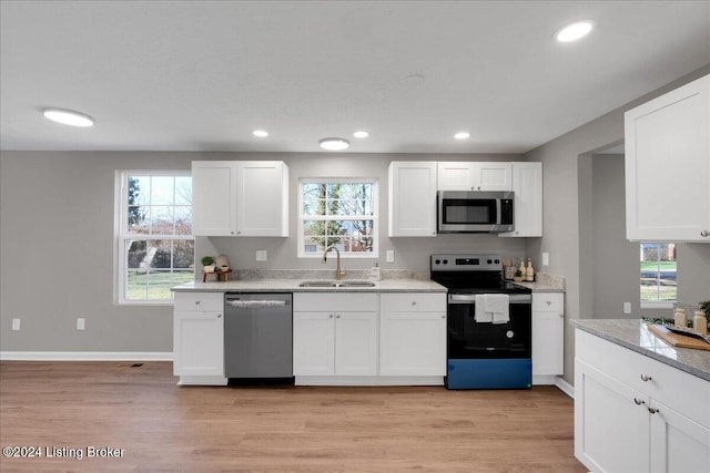 kitchen with appliances with stainless steel finishes, light hardwood / wood-style floors, white cabinetry, and sink