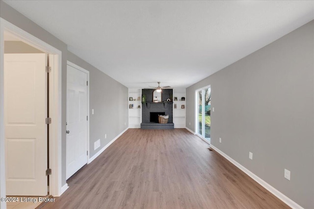 unfurnished living room featuring a fireplace, wood-type flooring, and ceiling fan