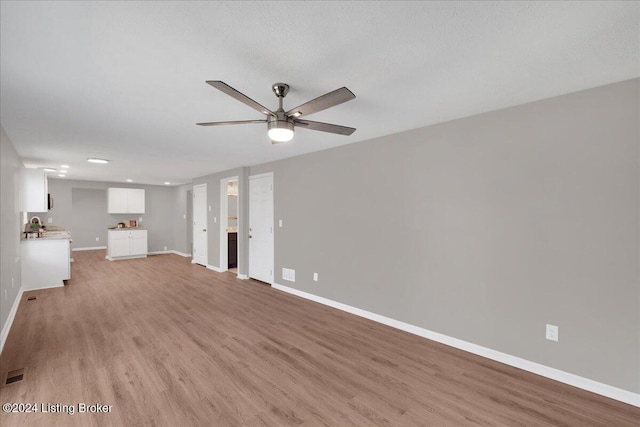 unfurnished living room with ceiling fan, light hardwood / wood-style floors, and a textured ceiling