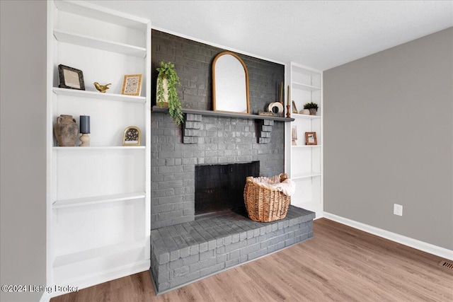 interior details with a fireplace, hardwood / wood-style floors, a textured ceiling, and built in shelves