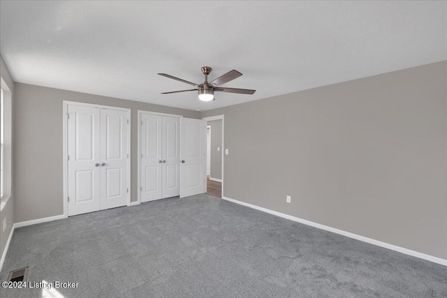 unfurnished bedroom featuring carpet flooring, ceiling fan, and two closets