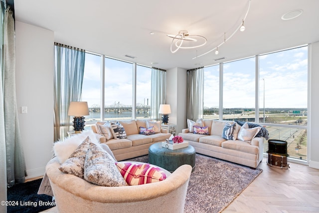 living room with light parquet flooring, a water view, an inviting chandelier, and floor to ceiling windows