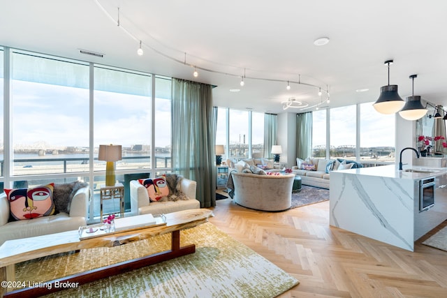 living room featuring light parquet floors, a wall of windows, and sink