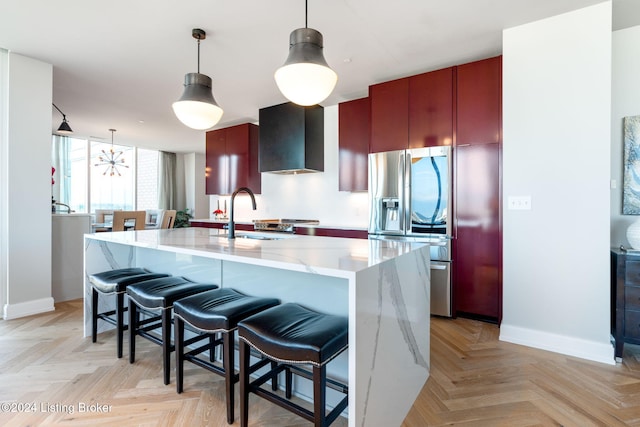 kitchen featuring pendant lighting, light parquet floors, sink, light stone counters, and stainless steel fridge with ice dispenser