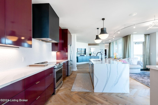 kitchen with sink, wall chimney exhaust hood, stainless steel appliances, light stone counters, and pendant lighting