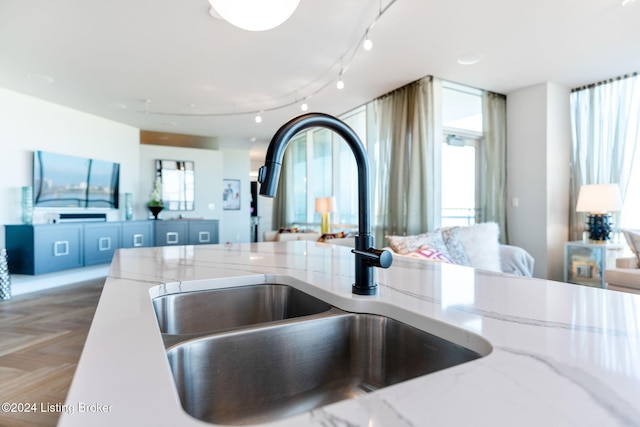 kitchen featuring light stone counters, parquet floors, and sink