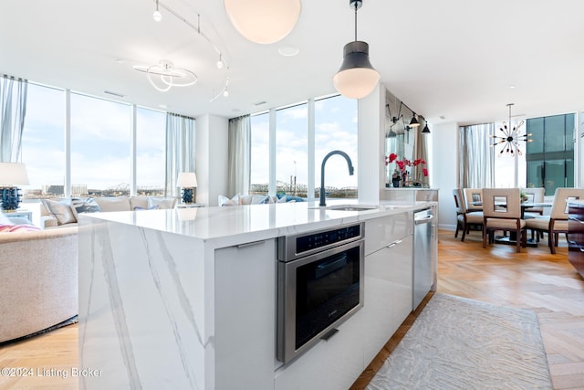 kitchen featuring a center island with sink, oven, sink, and hanging light fixtures