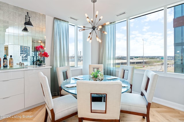 dining space with light parquet floors and a notable chandelier