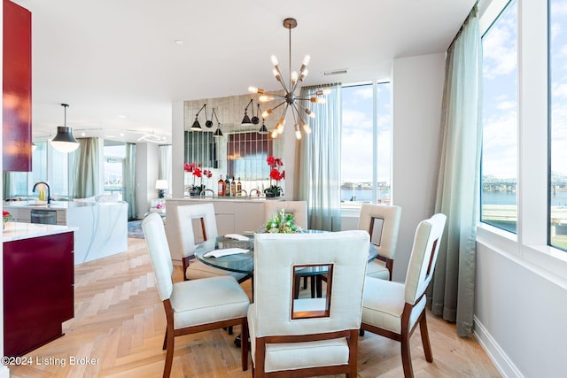 dining area featuring light parquet floors, a water view, plenty of natural light, and a notable chandelier