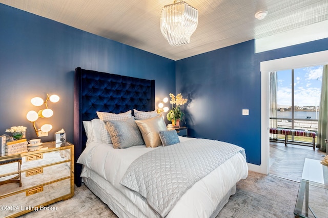 bedroom featuring a water view and an inviting chandelier