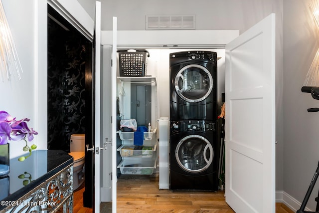 washroom with wood-type flooring and stacked washer and clothes dryer