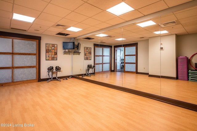 workout area featuring a paneled ceiling and light hardwood / wood-style floors