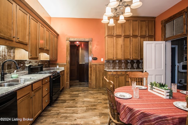 kitchen featuring black appliances, sink, hardwood / wood-style flooring, light stone counters, and a chandelier