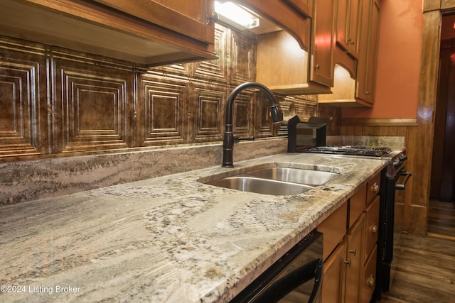 kitchen featuring wood walls, sink, dark hardwood / wood-style floors, black dishwasher, and light stone counters