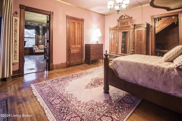 bedroom with a chandelier, hardwood / wood-style floors, and ornamental molding