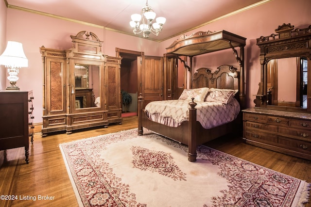 bedroom with hardwood / wood-style floors, crown molding, and an inviting chandelier