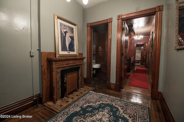 corridor with dark wood-type flooring and an inviting chandelier