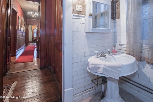 bathroom featuring hardwood / wood-style flooring, tile walls, and a chandelier