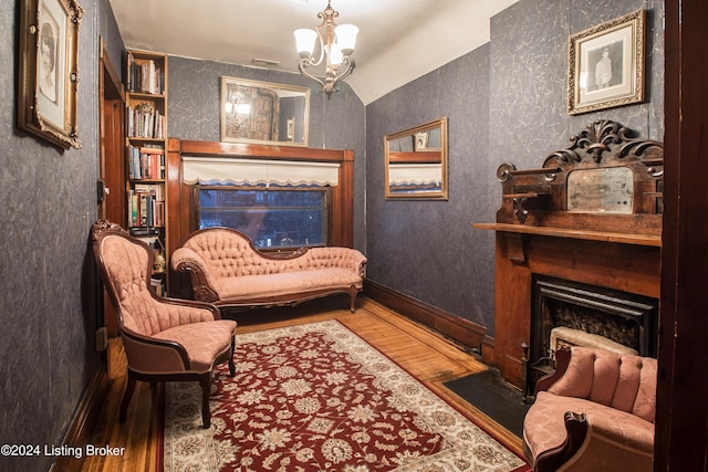 sitting room featuring hardwood / wood-style flooring, vaulted ceiling, and an inviting chandelier