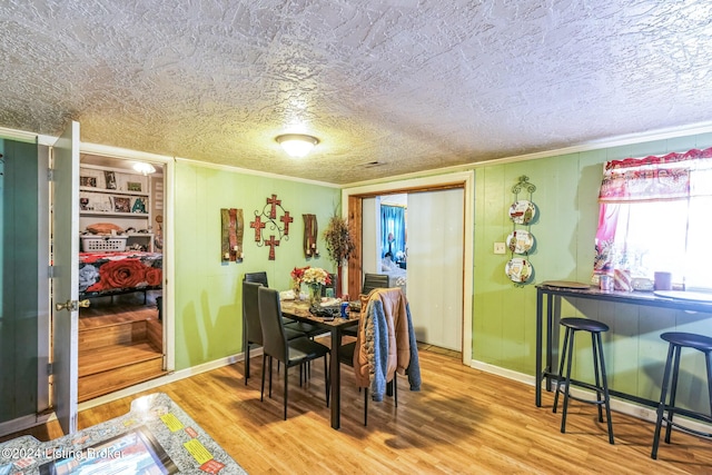 dining room with built in shelves, wood-type flooring, a textured ceiling, and a baseboard heating unit