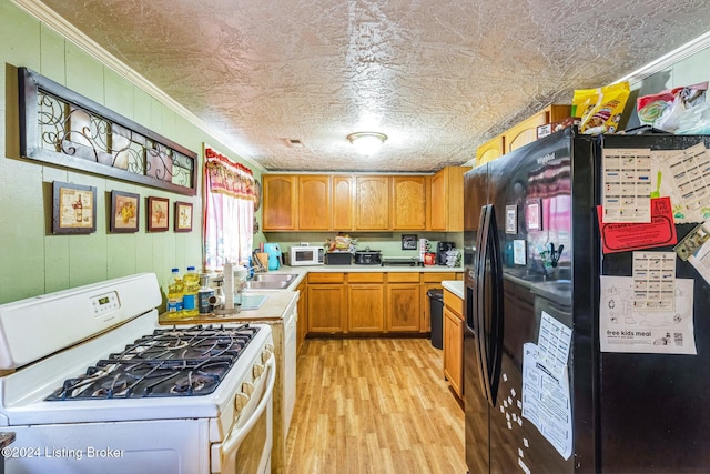 kitchen with white appliances, sink, ornamental molding, a textured ceiling, and light hardwood / wood-style floors