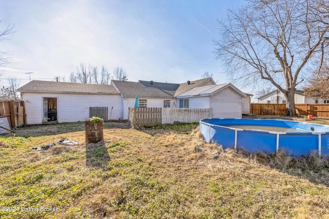 rear view of property featuring a fenced in pool and a yard