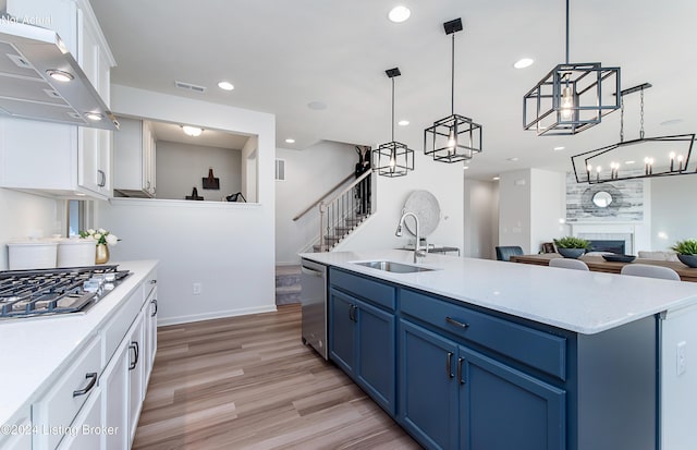 kitchen featuring a fireplace, sink, white cabinets, and blue cabinets