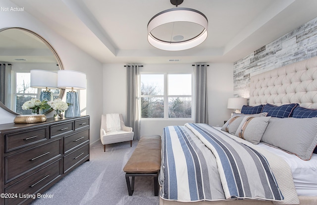 bedroom with a raised ceiling and carpet flooring