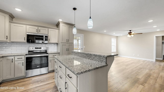 389 Williamsburg Dr, Mt Washington, KY 40047 - kitchen with backsplash, a kitchen island, a ceiling fan, light wood-type flooring, and stainless steel appliances