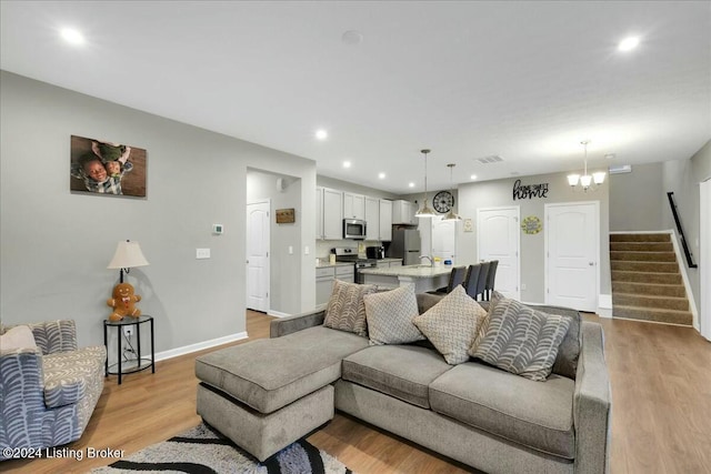 living room featuring a notable chandelier and light wood-type flooring