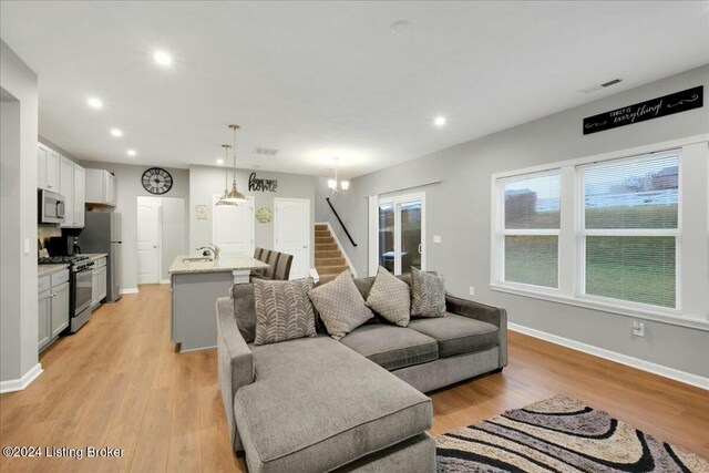 living room featuring a notable chandelier, sink, and light hardwood / wood-style flooring