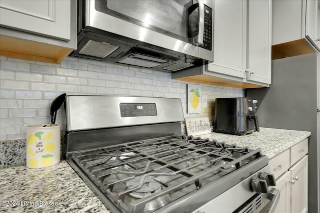 kitchen with light stone countertops, white cabinetry, appliances with stainless steel finishes, and tasteful backsplash