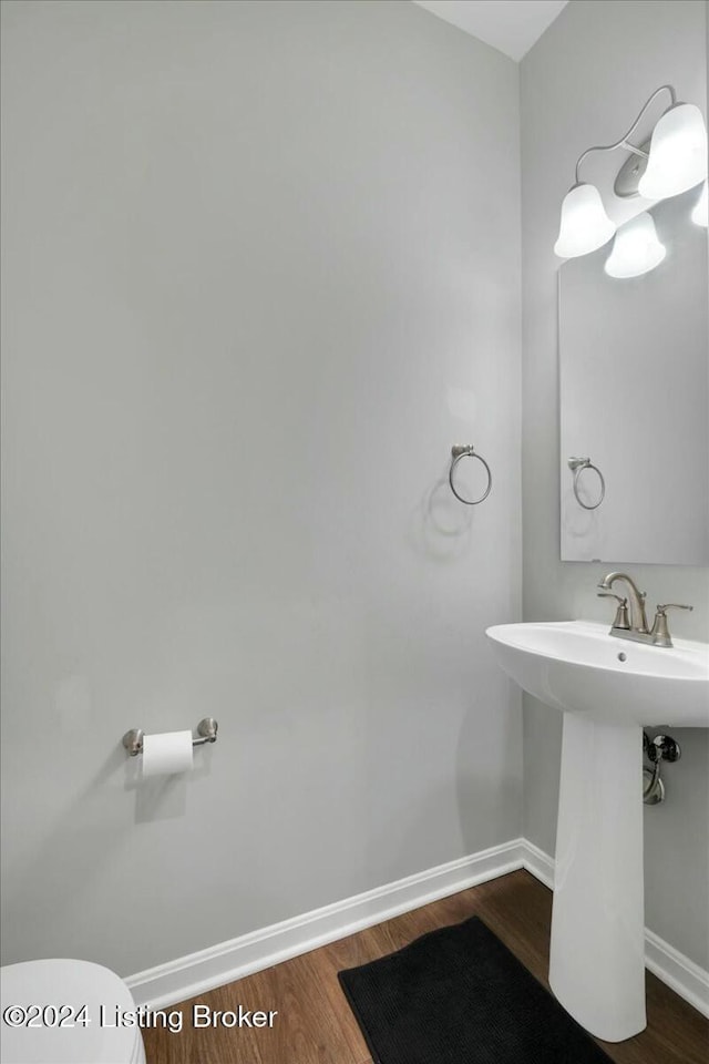 bathroom with toilet, wood-type flooring, and sink