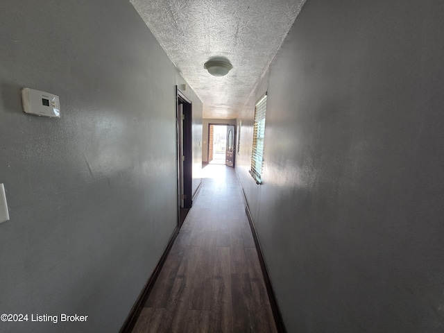 hallway with a textured ceiling and dark wood-type flooring