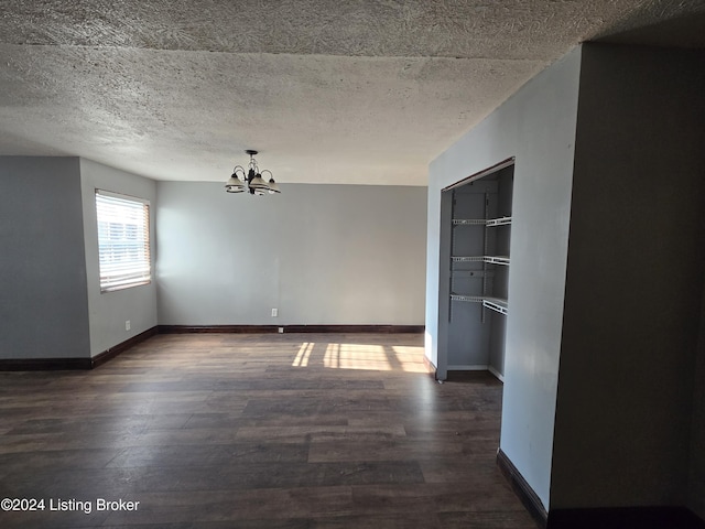 spare room featuring a textured ceiling, dark hardwood / wood-style floors, and an inviting chandelier