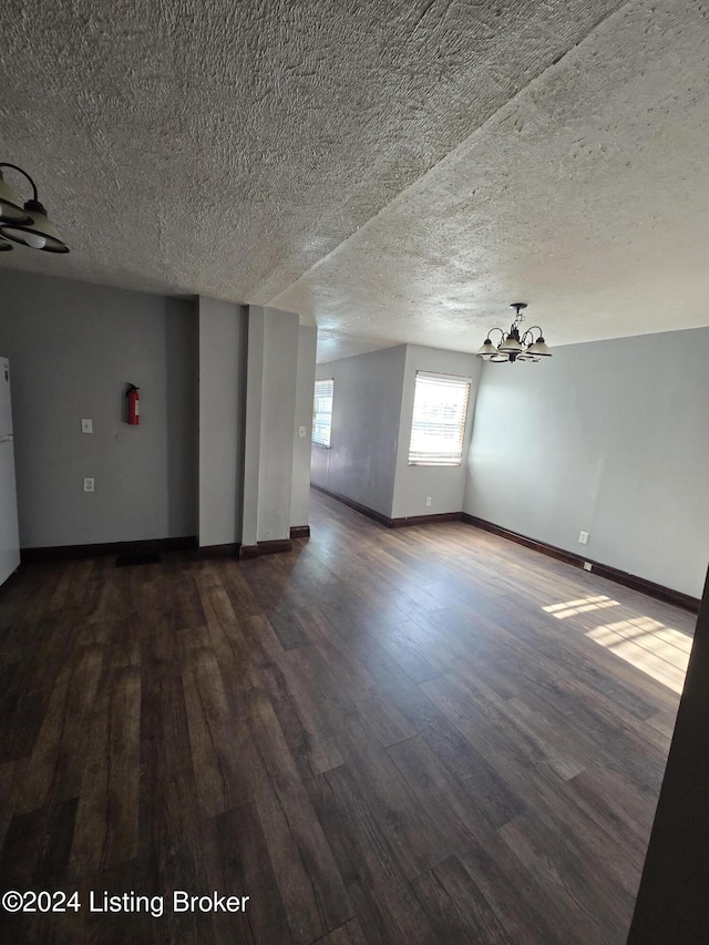 unfurnished room featuring ceiling fan with notable chandelier, dark hardwood / wood-style flooring, and a textured ceiling