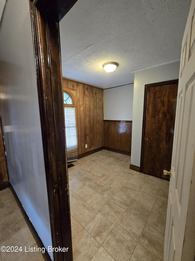 hallway with a textured ceiling and wooden walls