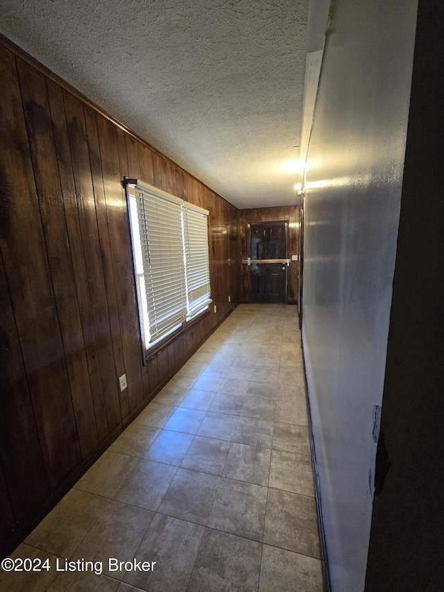 spare room featuring wood walls and a textured ceiling