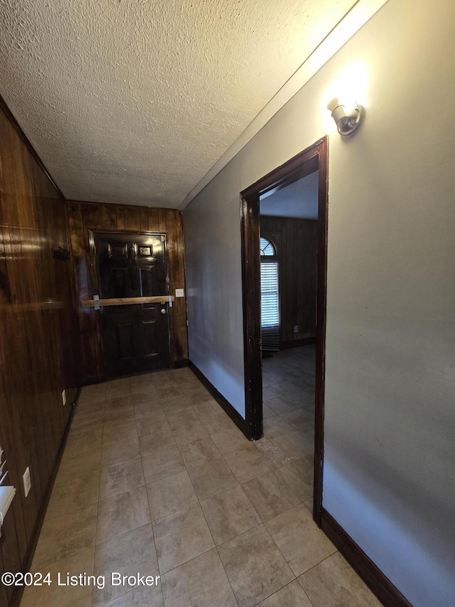 hallway featuring wooden walls and a textured ceiling