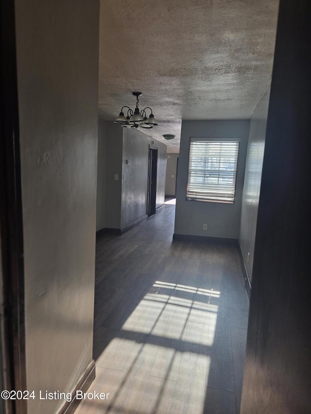 spare room with a notable chandelier, wood-type flooring, and a textured ceiling