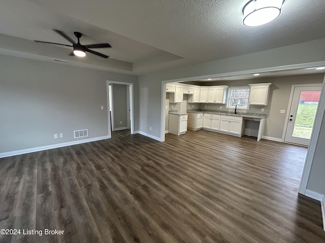 unfurnished living room featuring a textured ceiling, ceiling fan, dark wood-type flooring, and sink