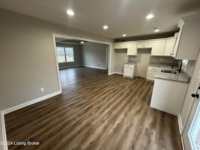 kitchen featuring dark hardwood / wood-style floors, light stone counters, white cabinetry, and sink