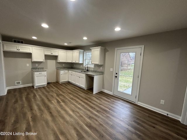 kitchen featuring light stone countertops, white cabinetry, sink, and dark wood-type flooring